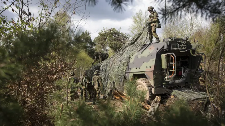 Militairen camoufleren een Boxer-ambulance.