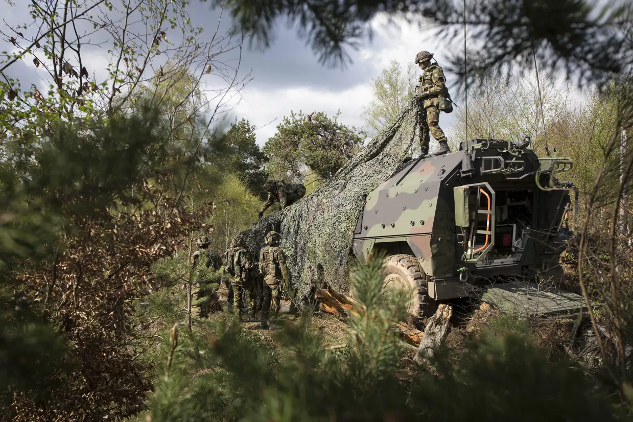 Militairen camoufleren een Boxer-ambulance.