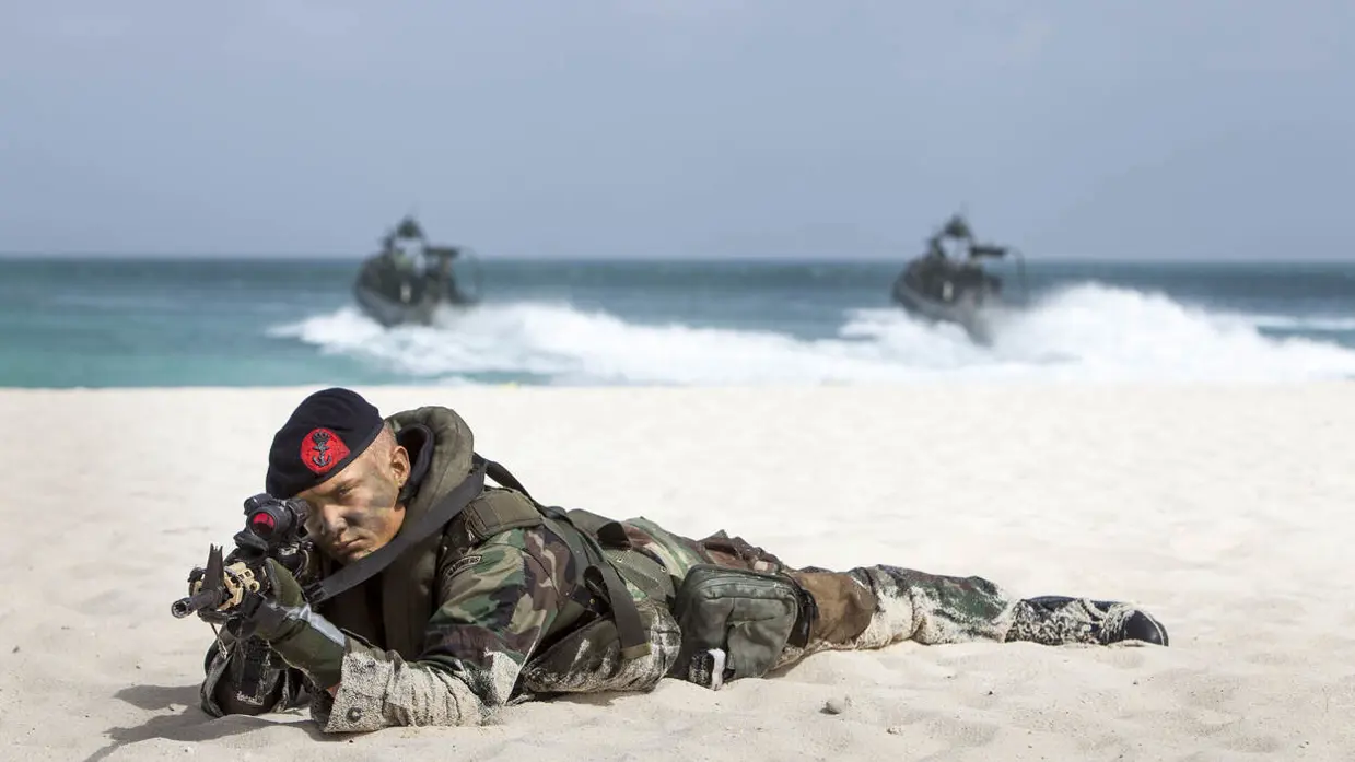 Een marinier liggend op zijn buik in het oude uniform op het strand van Sint-Maarten.