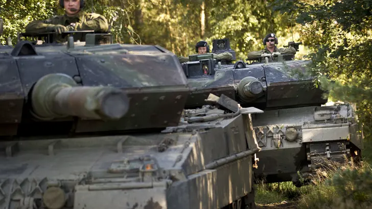 2 Leopard-gevechtstanks rijden achter elkaar in een bos.