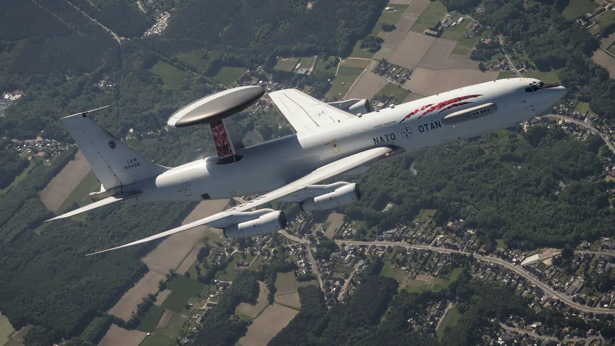AWACS-vliegtuig met 'tiger'-beschildering boven bewoond gebied.