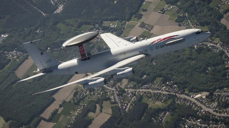 AWACS-vliegtuig met 'tiger'-beschildering boven bewoond gebied.