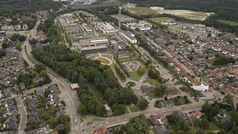 Luchtfoto van een gebouwencomplex, omzoomd met bomen en grenzend aan woonwijken.