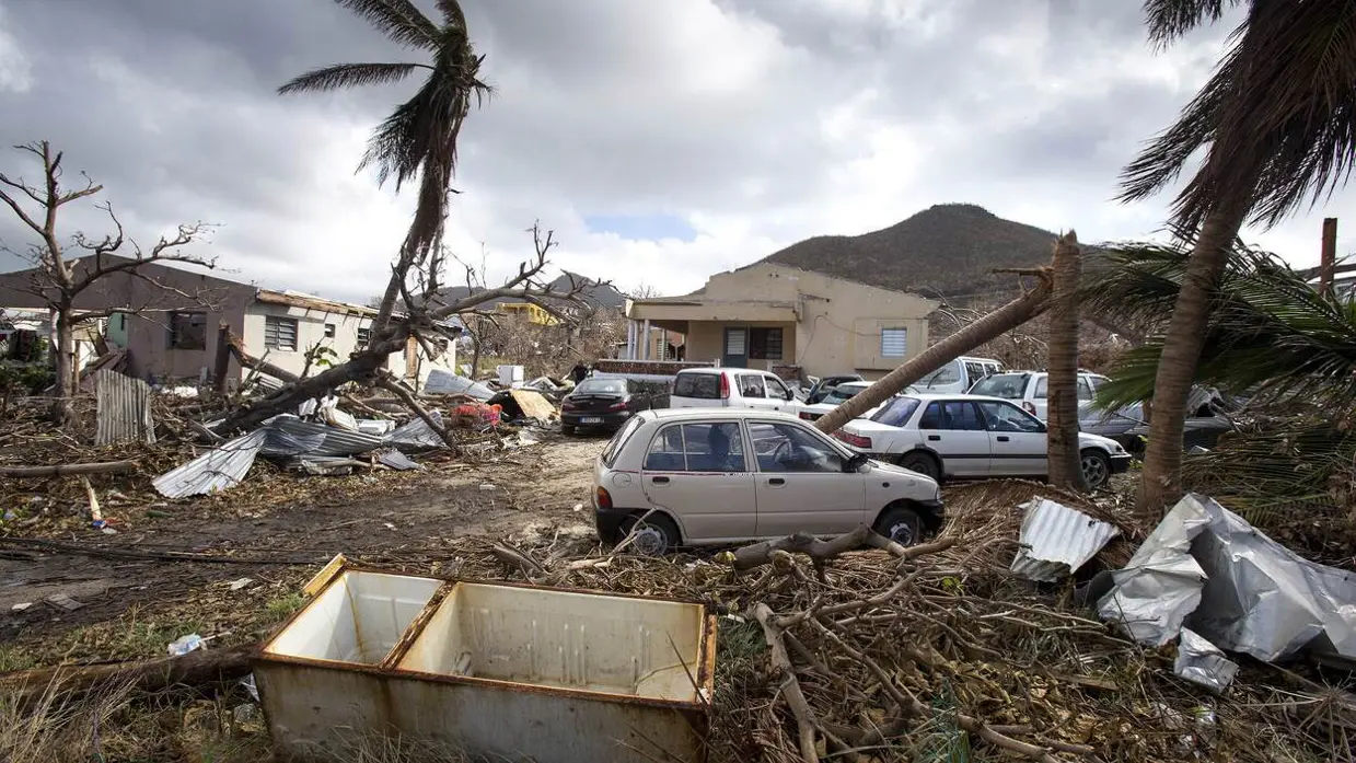 Een woonwijk na de verwoestende passage van orkaan Irma, met zwaar beschadigde huizen, auto’s en omgevallen palmbomen.