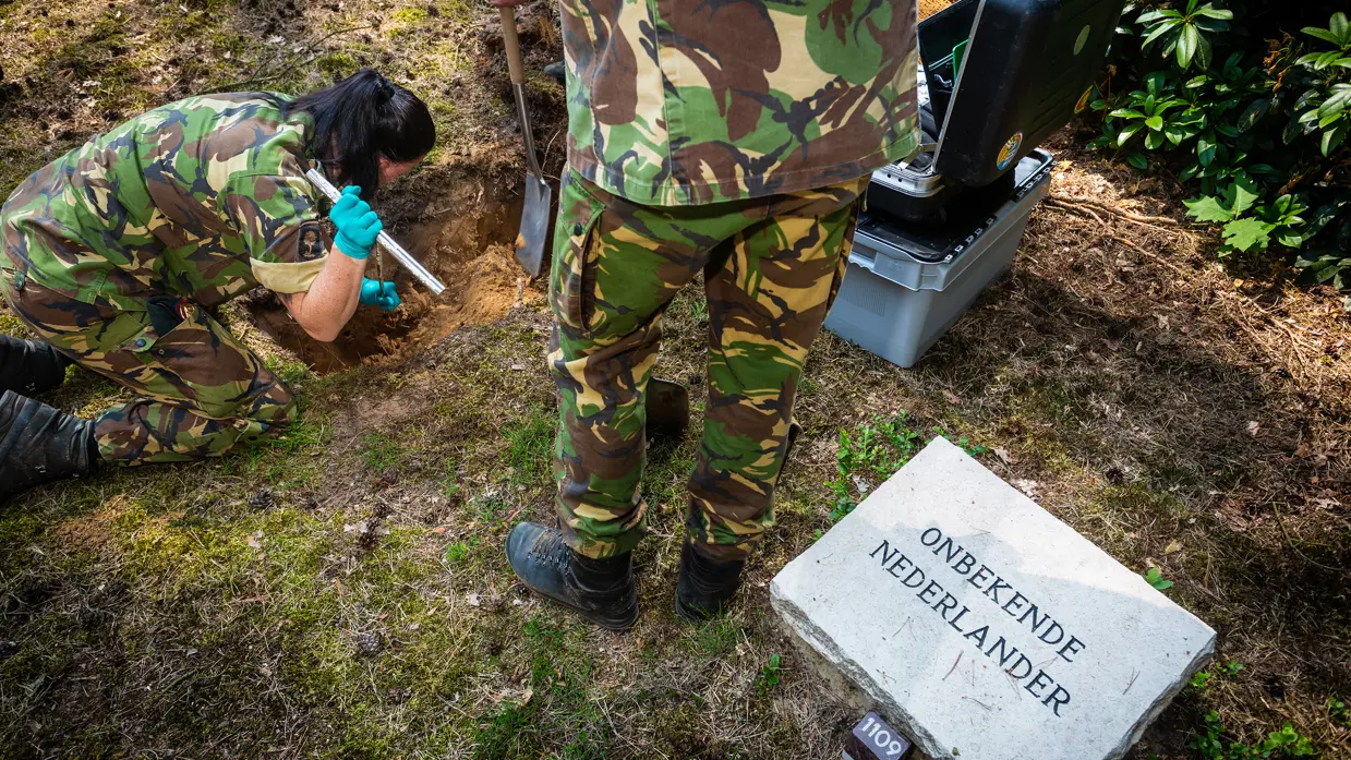 Militairen van de Bergings-en Identificatiedienst Koninklijke Landmacht openen een graf van een onbekende Nederlander.