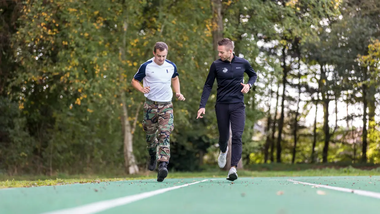 2 mannen lopen op een groene atletiekbaan.