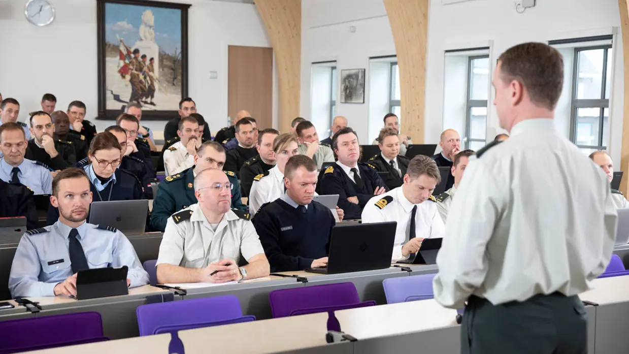Militaire studenten in collegezaal, met spreker.