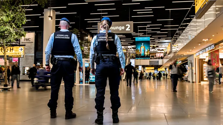 Een mannelijke en vrouwelijke marechaussee, op de rug gezien.