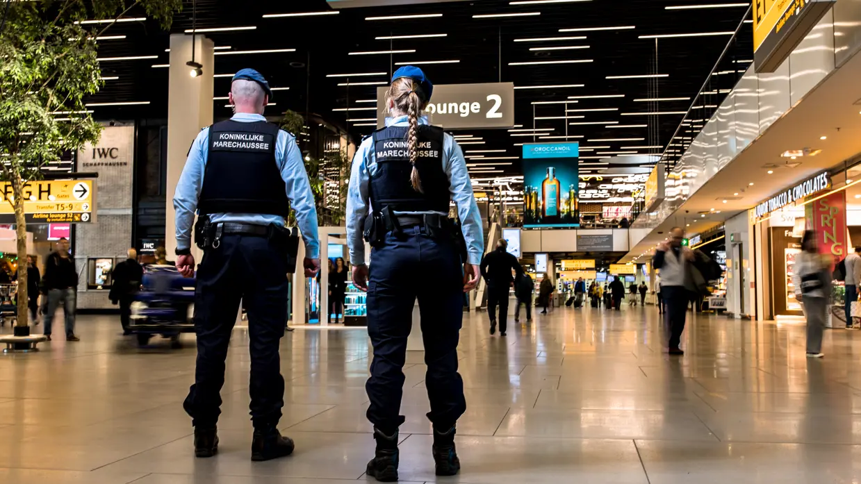 Een mannelijke en vrouwelijke marechaussee, op de rug gezien.