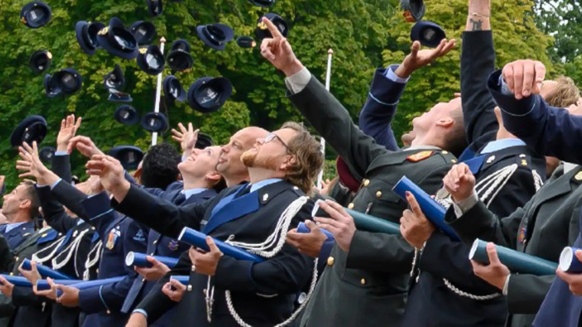 Studenten gooien traditiegetrouw hun petten in de lucht met hun bul onder de arm.