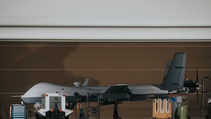 Een MQ-9 Reaper in een openstaande hangaar van de linker zijkant bezien.