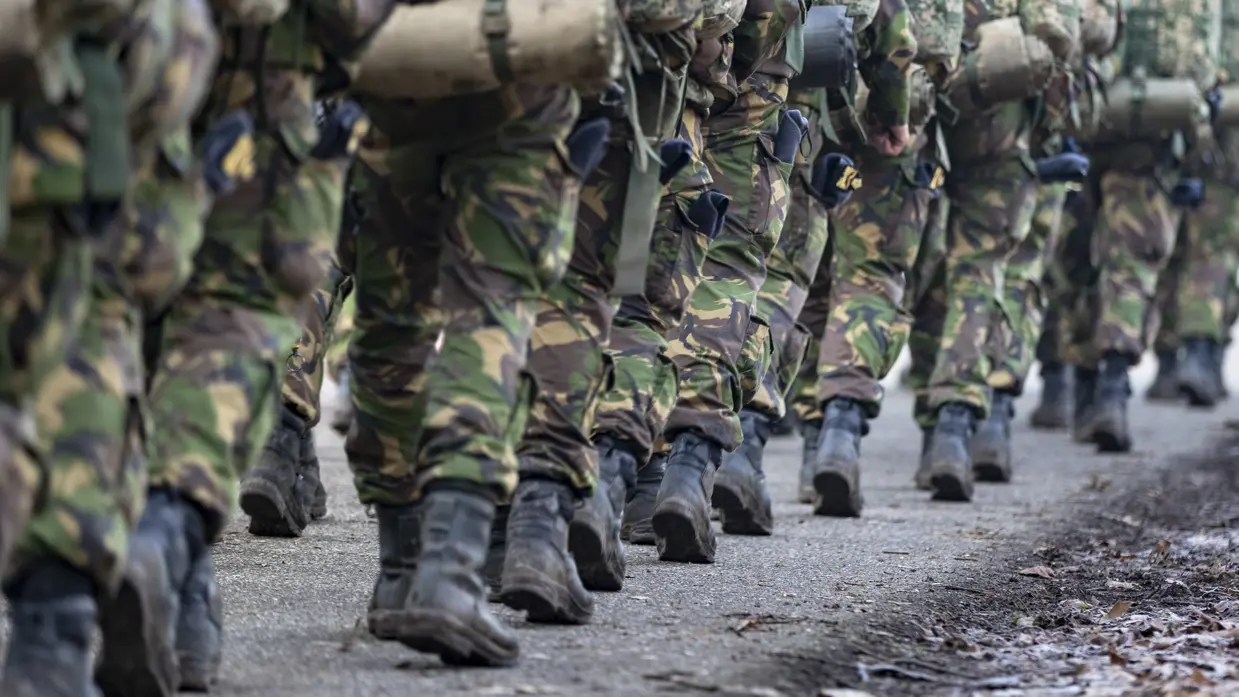 Close-up van benen van een marcherende groep militairen.