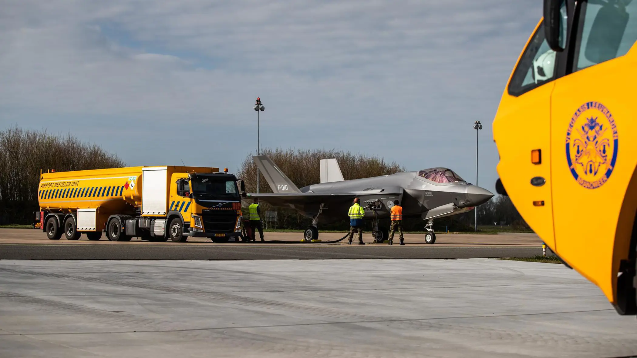 Een grote, gele tankwagen staat bij een F-35 en voorziet het toestel van brandstof.
