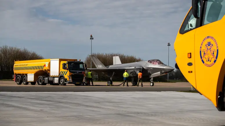 Een grote, gele tankwagen staat bij een F-35 en voorziet het toestel van brandstof.