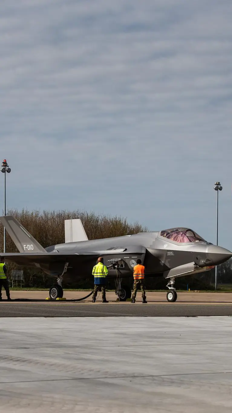 Een grote, gele tankwagen staat bij een F-35 en voorziet het toestel van brandstof.