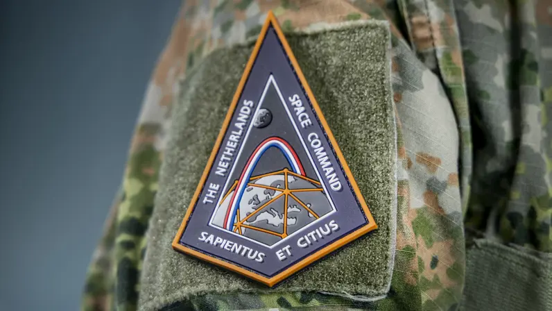 Close-up van een Space Command-badge op een camouflage-tenue.