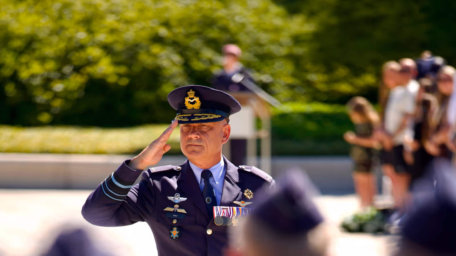 Luitenant-generaal André Steur salueert naar aan aantal militairen die wazig in de voorgrond te zien zijn.