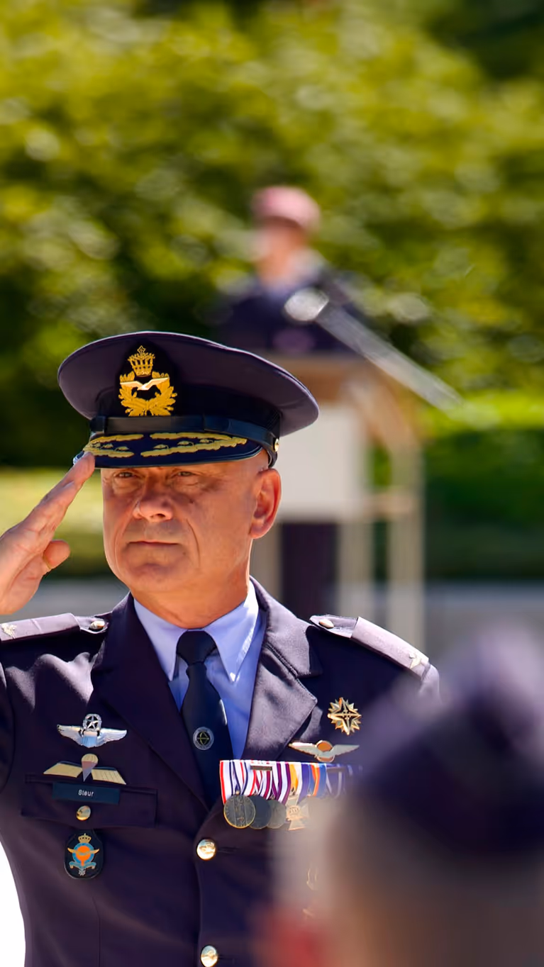 Luitenant-generaal André Steur salueert naar aan aantal militairen die wazig in de voorgrond te zien zijn.