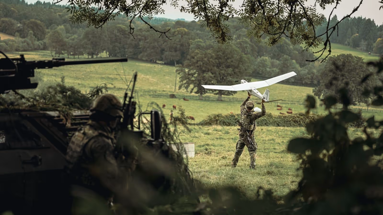 Een militair werpt een drone vooruit in een grasveld.