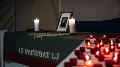 Mix van beelden van Delano. We zien onder meer zijn kist gedragen door militairen, een groepsappel met trompet en een herdenkingsplek voor de gevallen militair.&nbsp;