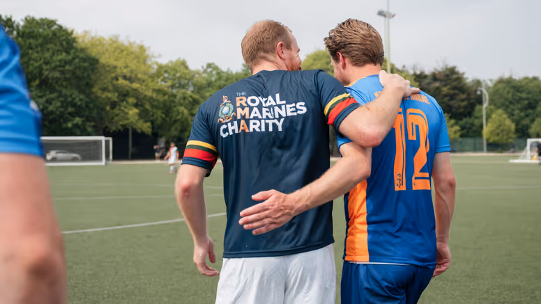 Nederlandse en Engelse mariniers lopen gearmd op het voetbalveld.