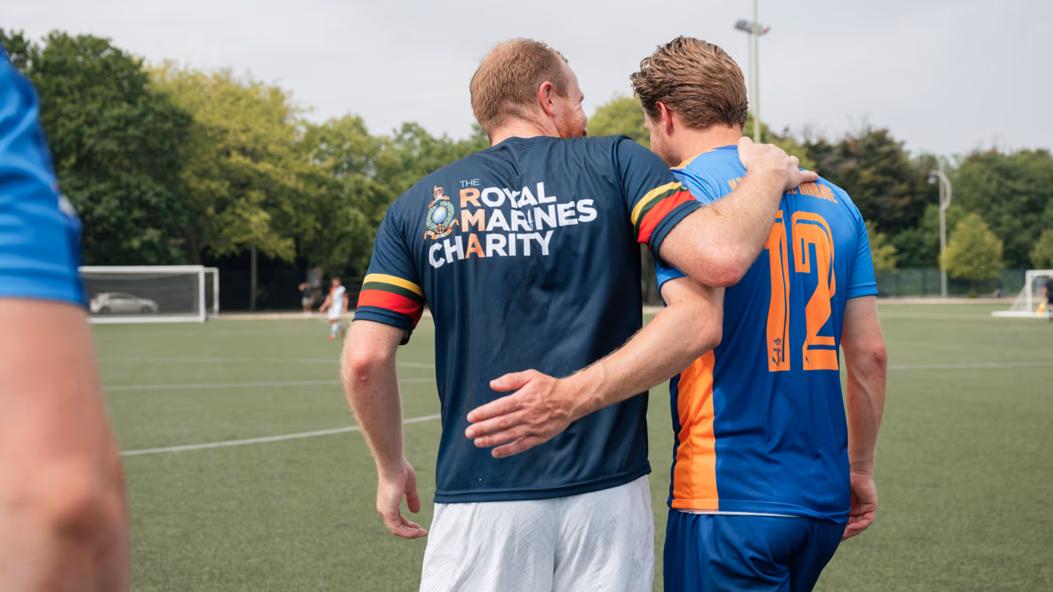 Nederlandse en Engelse mariniers lopen gearmd op het voetbalveld.