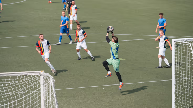 Een keeper vangt de bal.