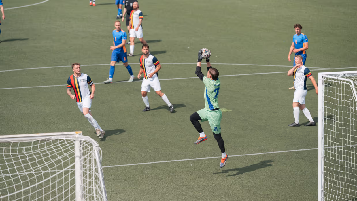 Een keeper vangt de bal.