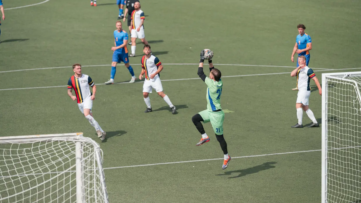 Een keeper vangt de bal.