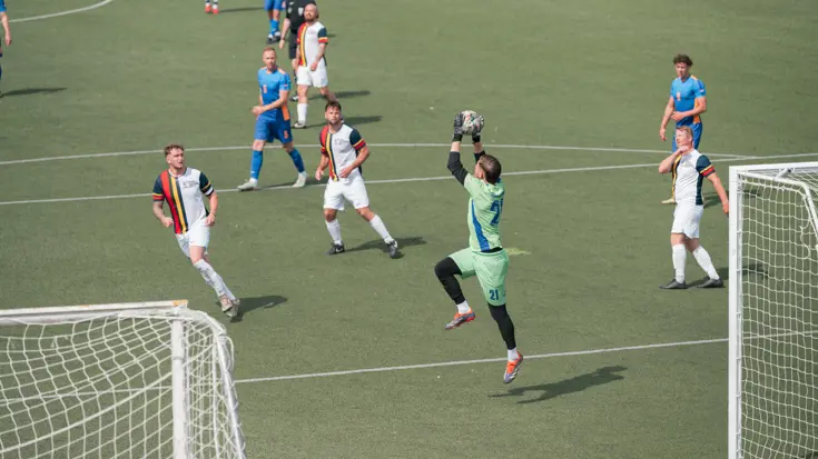 Een keeper vangt de bal.