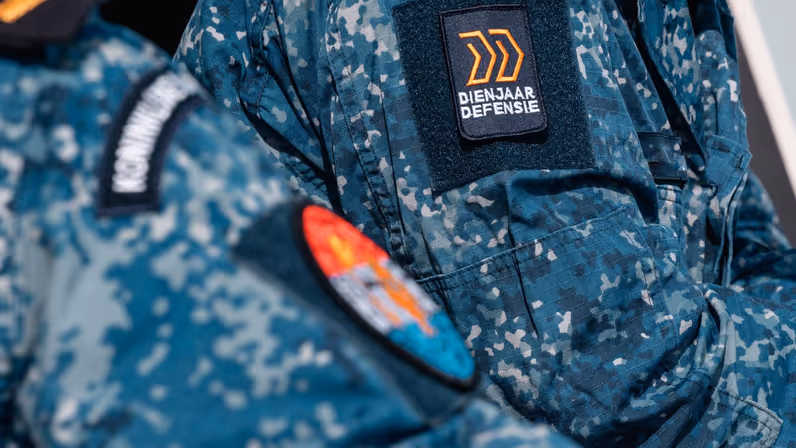 Mouw van een boordtenue met de badge van het Dienjaar.