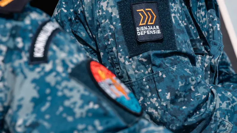 Mouw van een boordtenue met de badge van het Dienjaar.