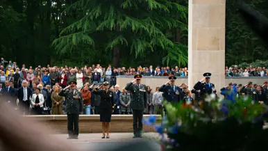 Vijf militairen van land- en luchtmacht, marine en marechaussee brengen de eregroet voor het monument. Achter hen staan lange rijen publiek.