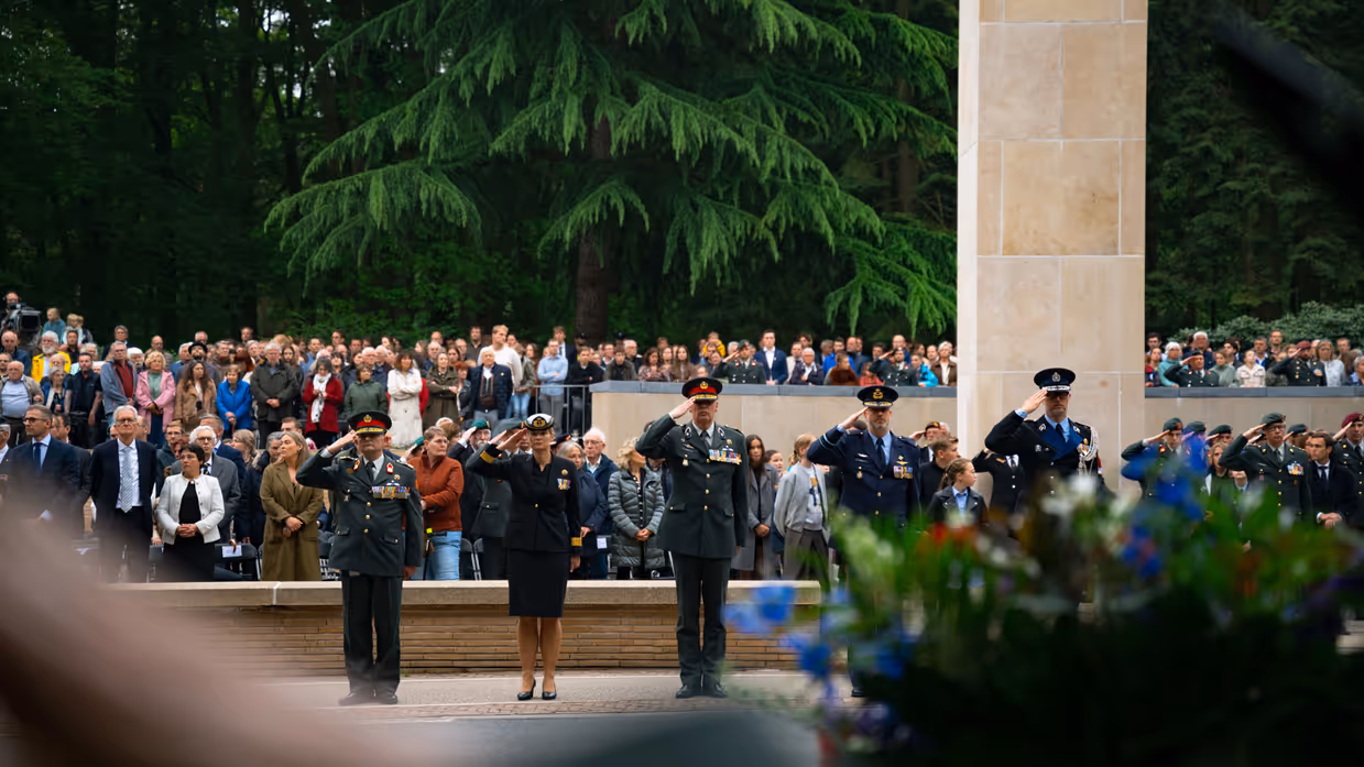  Militairen staan in de houding   Mensen lopen langs het monument 