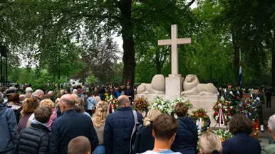  Militairen staan in de houding   Mensen lopen langs het monument 