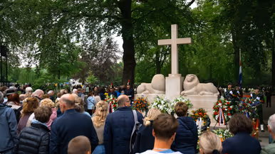  Militairen staan in de houding   Mensen lopen langs het monument 