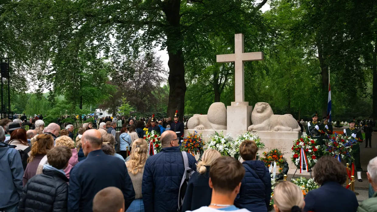  Militairen staan in de houding   Mensen lopen langs het monument 