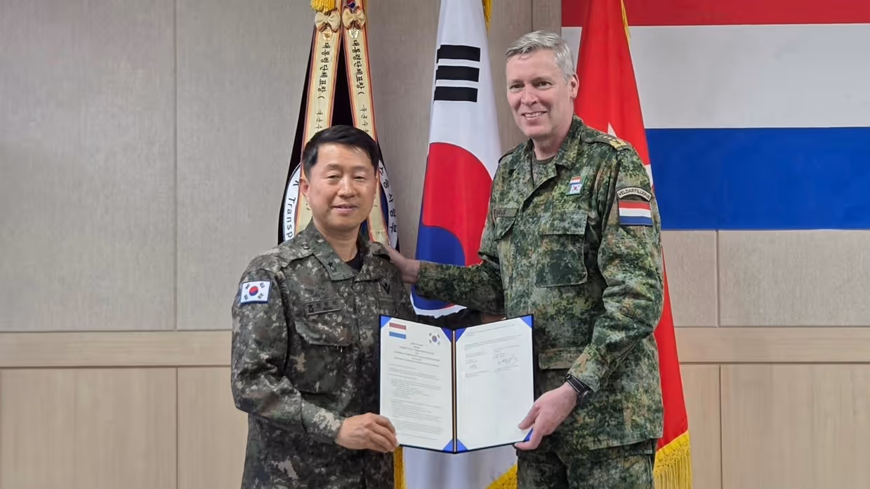 Twee hoge militairen laten een document zien dat ze zojuist hebben ondertekend.