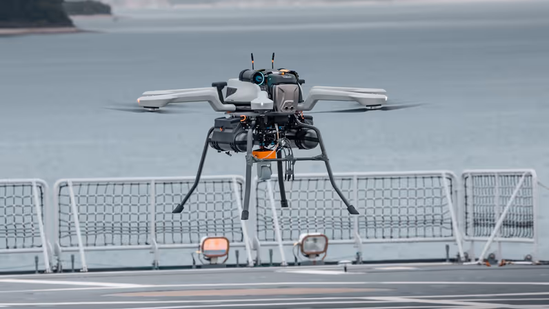 Een drone hangt boven een helidek.