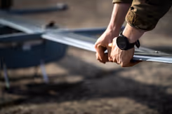 Militair houdt vleugel van drone vast.