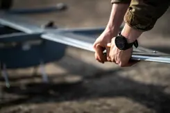 Militair houdt vleugel van drone vast.