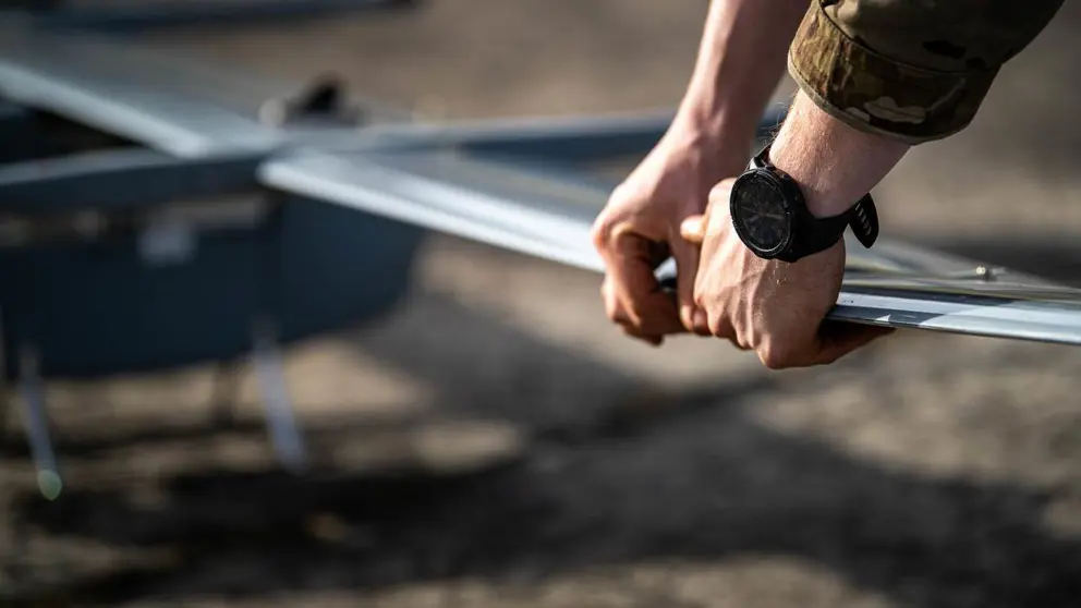 Militair houdt vleugel van drone vast.
