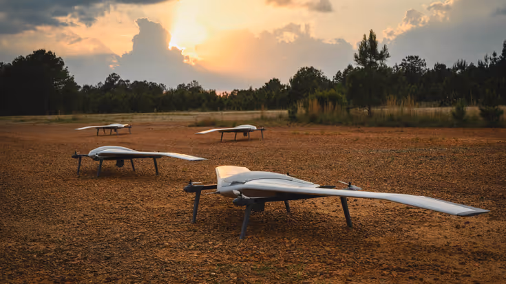 Een aantal drones op een veld bij een laaghangend zonnetje. 