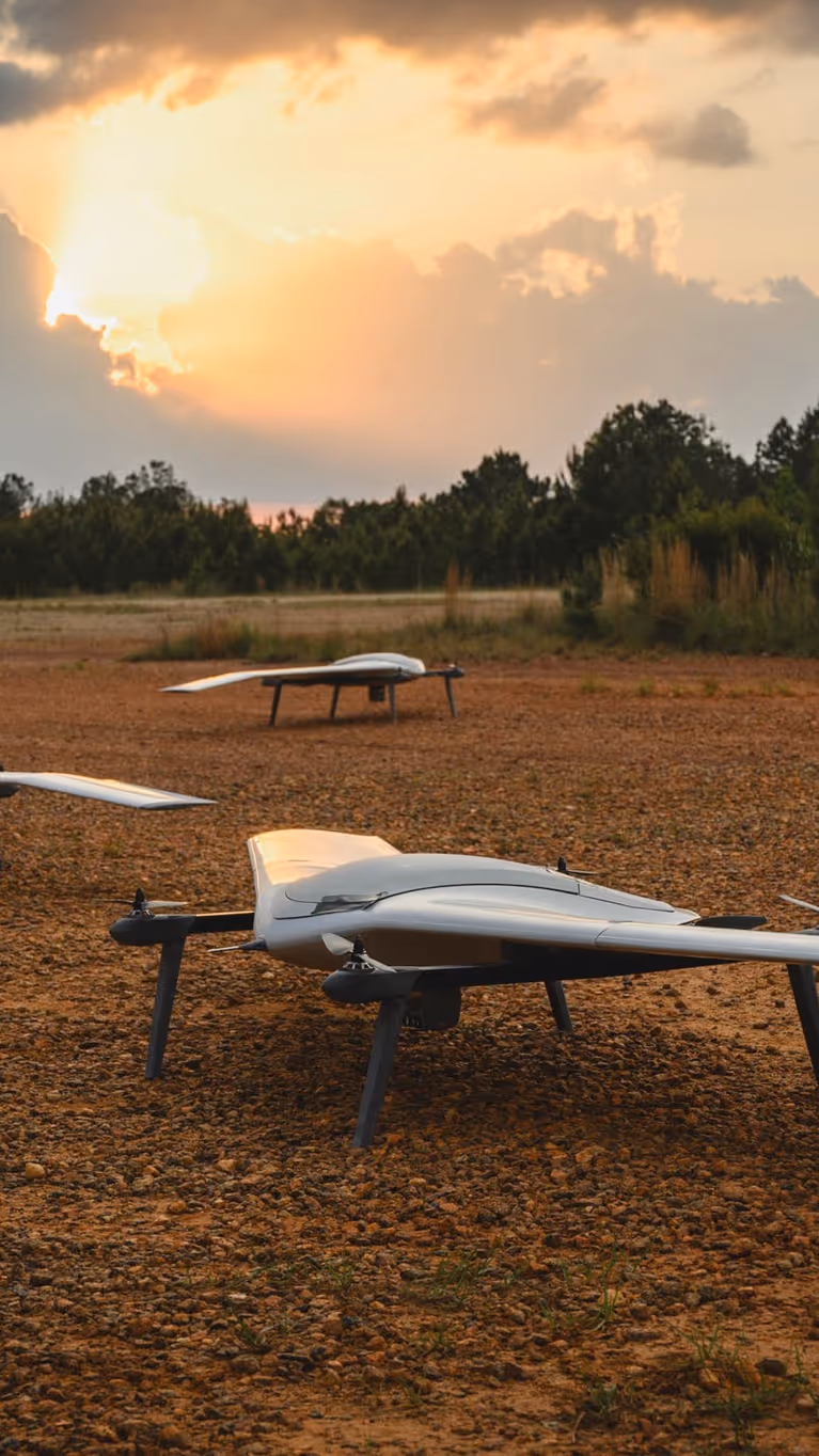 Vier drones staan op open veld in bosrijke omgeving.