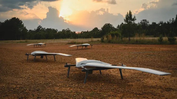 Een aantal drones op een veld bij een laaghangend zonnetje. 