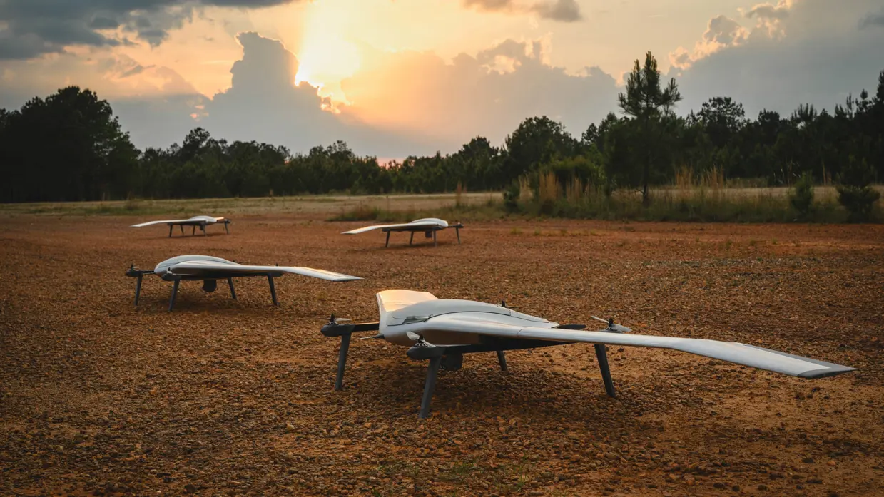 Een aantal drones op een veld bij een laaghangend zonnetje. 