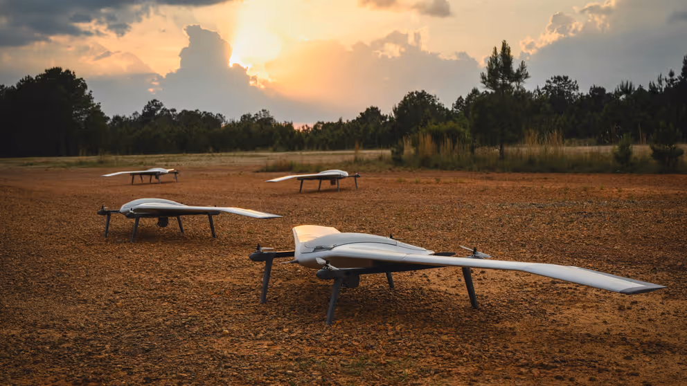Vier drones staan op open veld in bosrijke omgeving.
