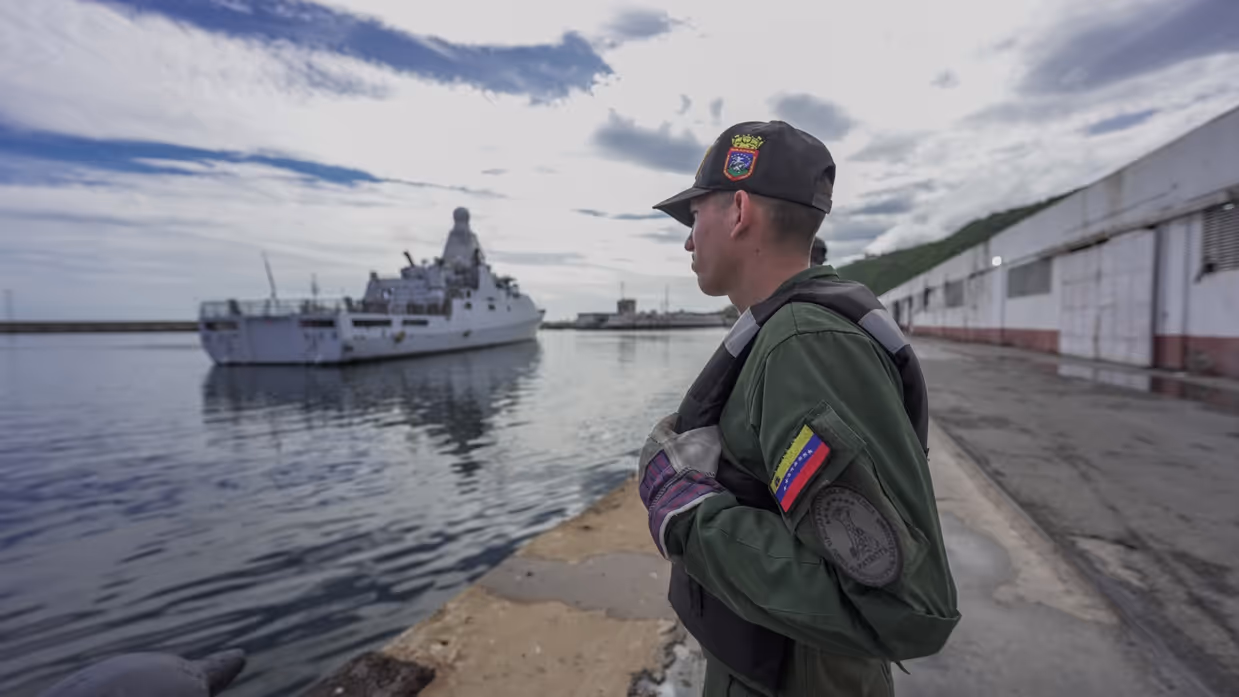 Een Venezolaanse militair op de kade met daarachter het patrouilleschip Zr.Ms. Groningen.