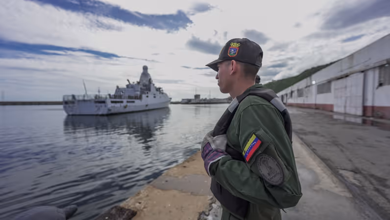 Een Venezolaanse militair op de kade met daarachter het patrouilleschip Zr.Ms. Groningen.