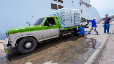Een oude pick-up truck wordt volgeladen met pallets waterflessen. 